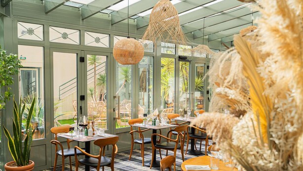 Un restaurante con techo de vidrio, lámparas colgantes de mimbre y piso a cuadros.