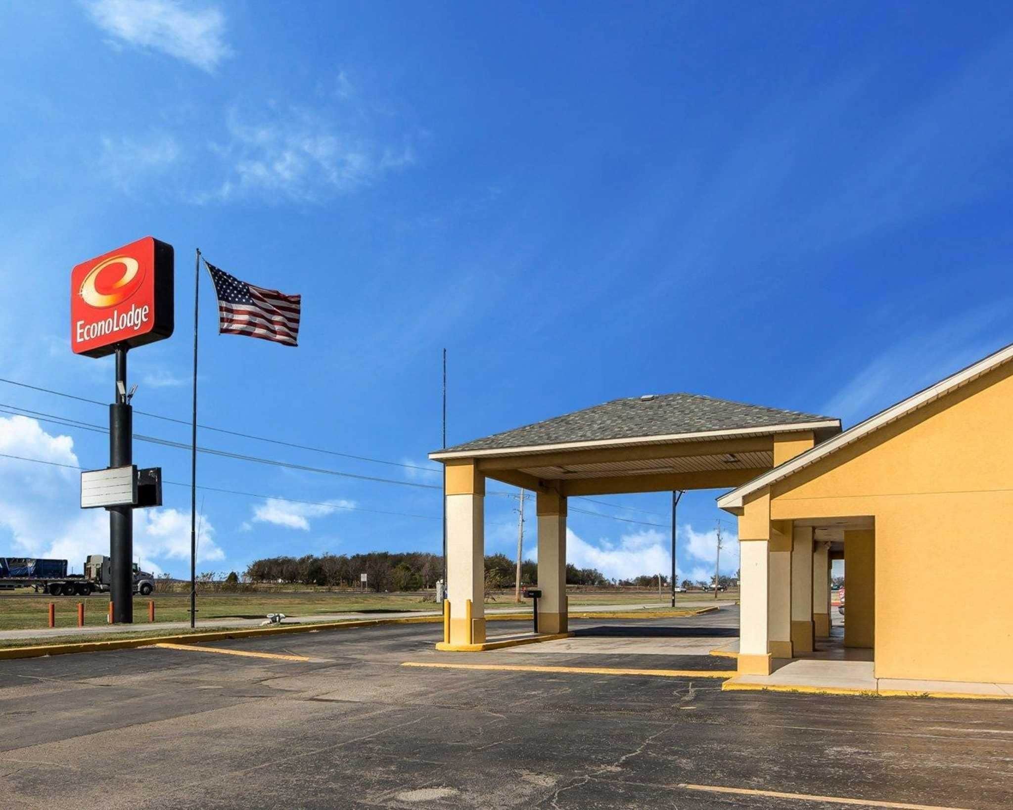 A parking lot with a covered area, a sign for EconoLodge, and an American flag.