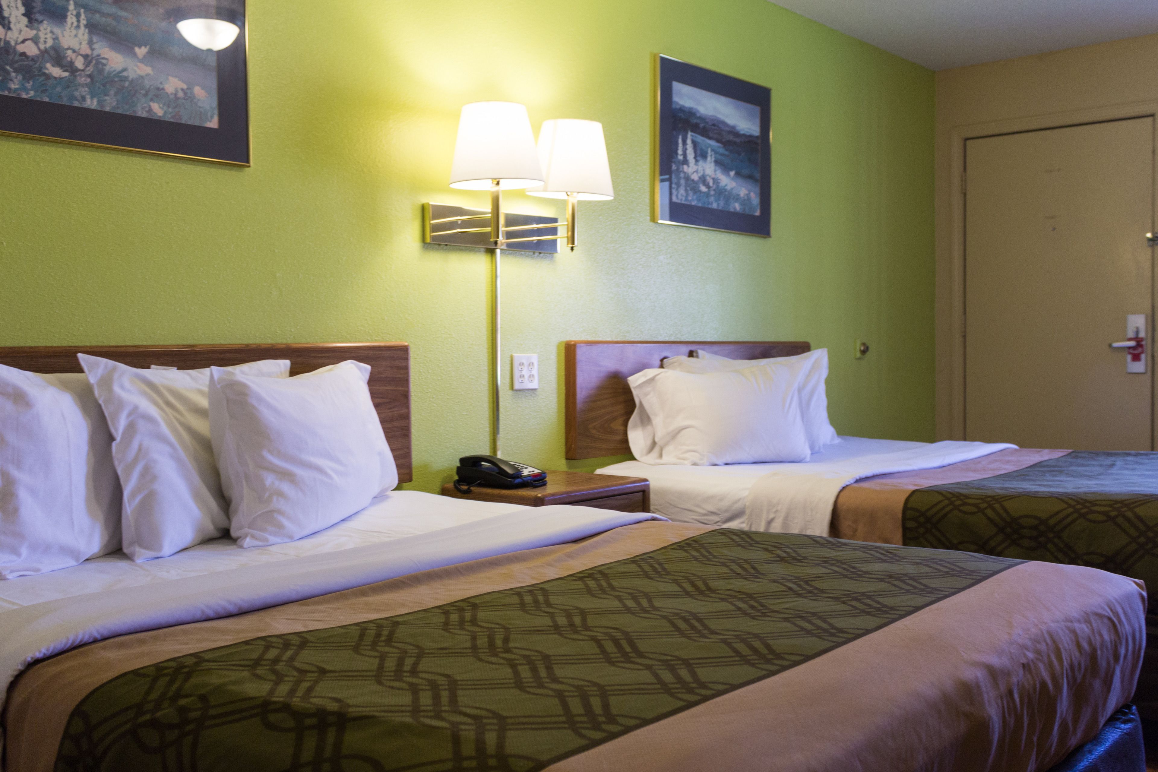 Ein Hotelzimmer mit zwei Betten, einem Nachttisch mit Telefon und einer Wandleuchte.