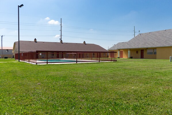 A building with a fenced pool area, a flat roof, and a clear sky.