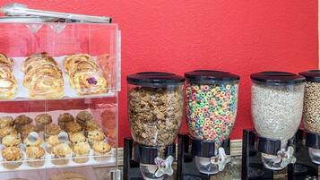 A breakfast display with pastries, muffins, and cereal options.