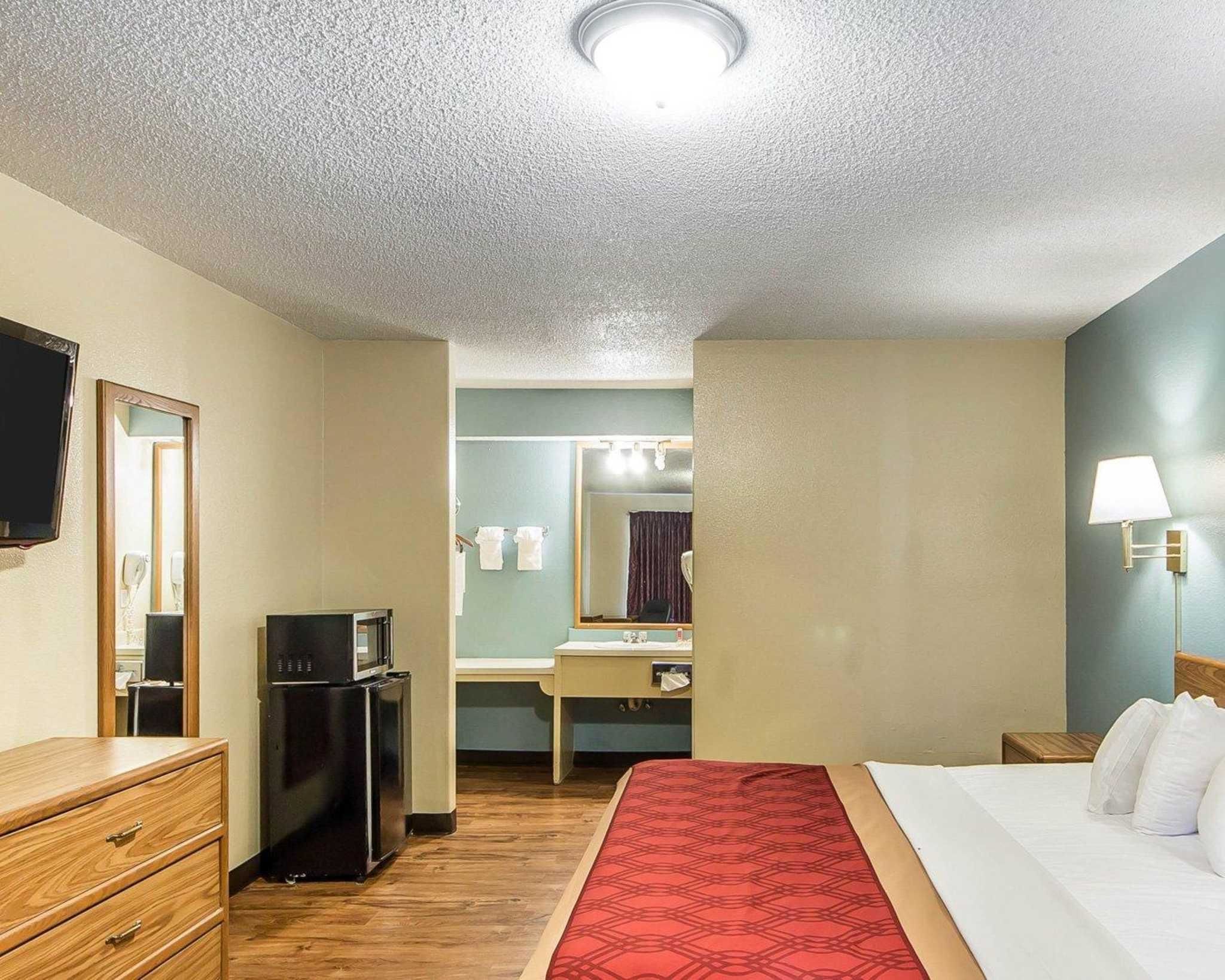 Une chambre d’hôtel comprenant un lit, une commode, un bureau avec un miroir, un four à micro-ondes et une lampe.