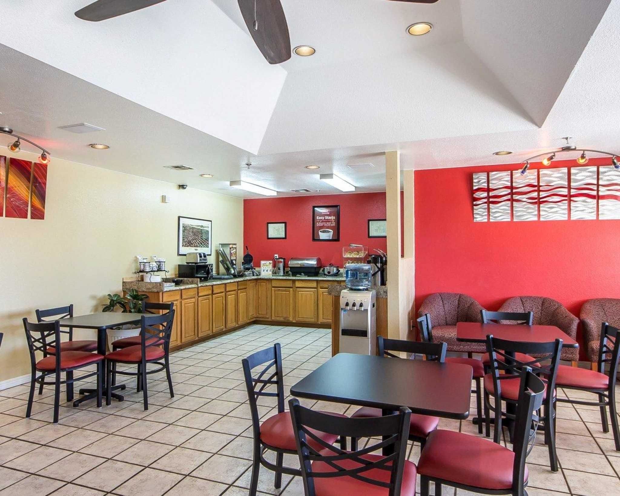 A restaurant with a kitchen area, red walls, and tiled flooring.