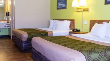 A hotel room with two beds, a bedside table with a lamp, a mirror, and a painting on the wall.