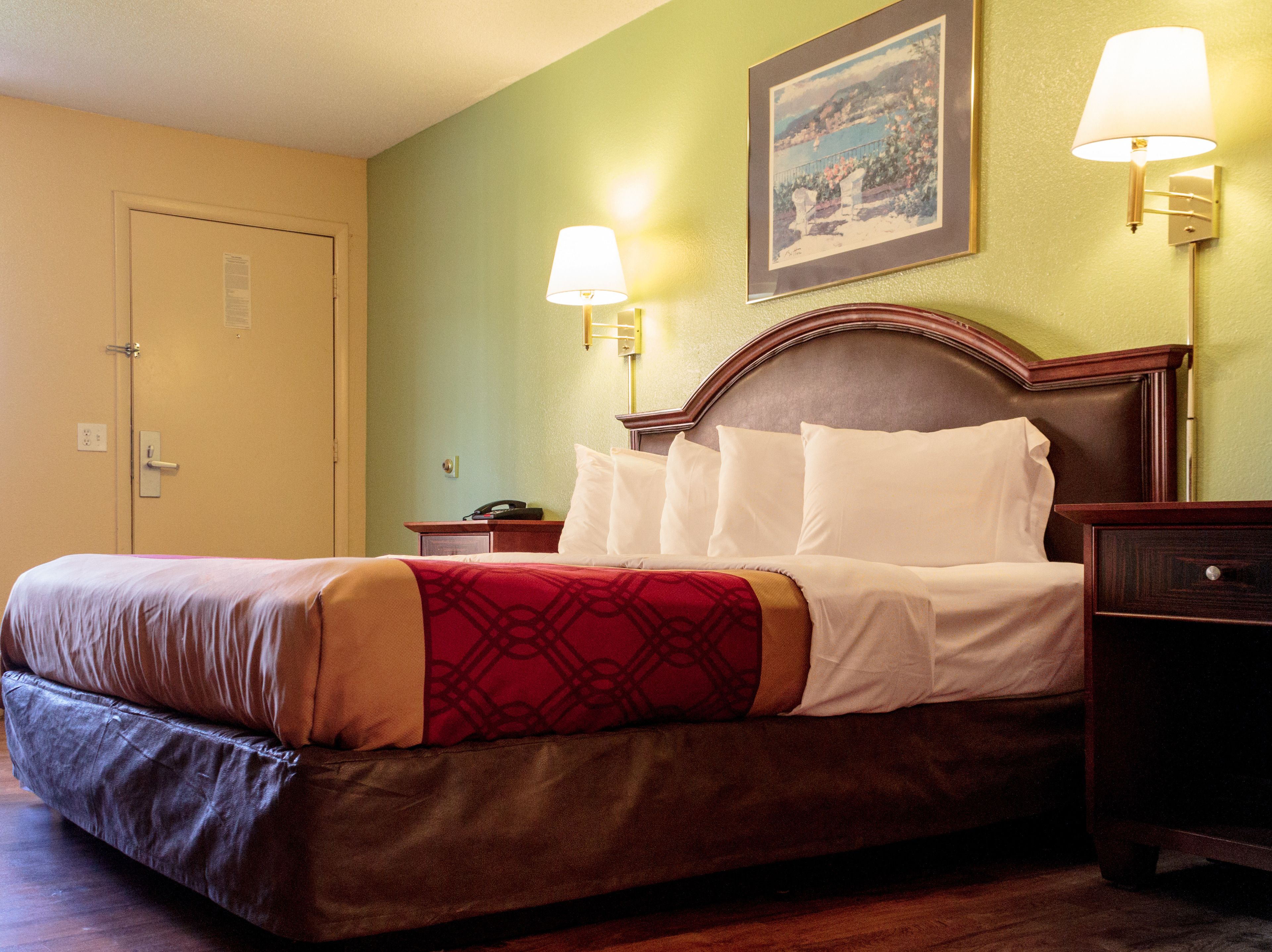 A hotel room with a bed, nightstands, a lamp, and a framed picture on the wall.