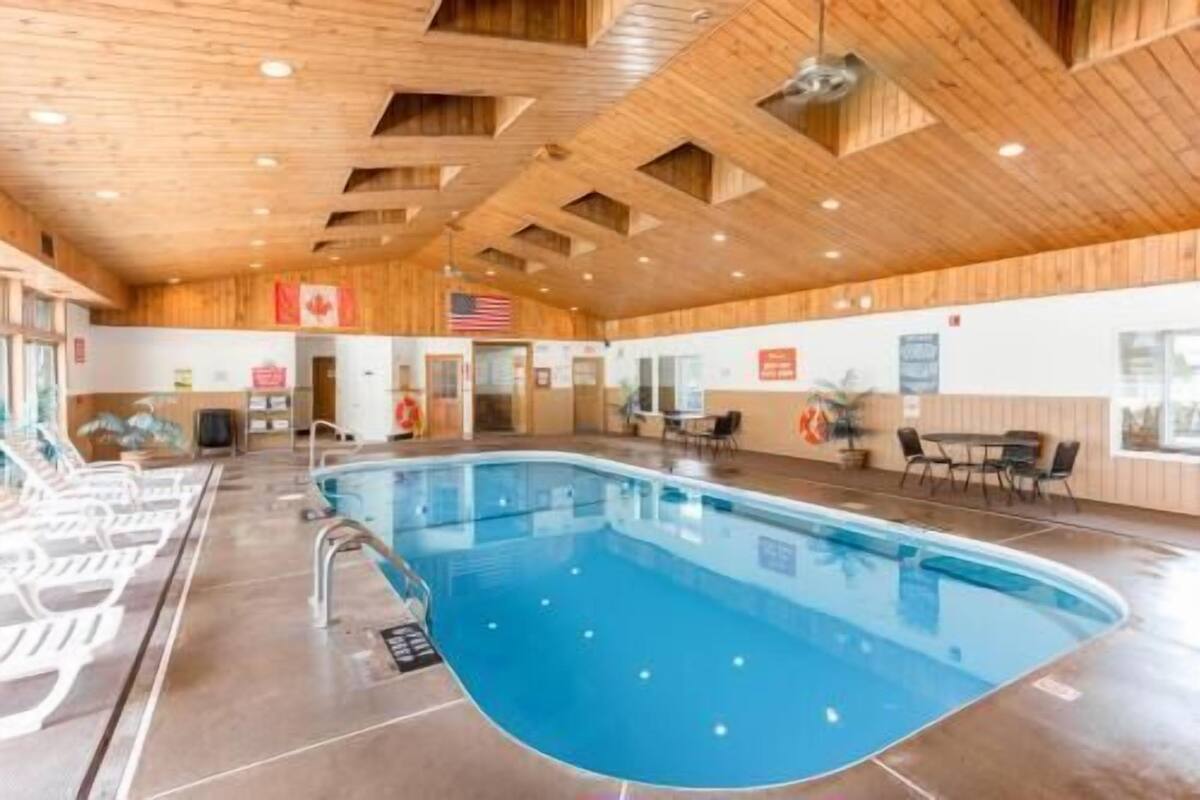 An indoor swimming pool with wooden ceiling beams, a lifeguard stand, and a Canadian flag.