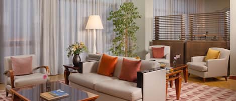 A modern living room with a sofa, armchairs, a coffee table, and a lamp.