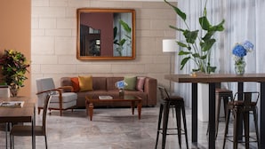 A modern living room with a brown sofa, a coffee table, and a dining area with bar stools. - NH Ancona (Ancona)