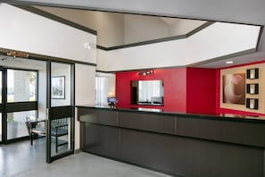 A reception area with a glass door entrance, a reception desk, and a red accent wall. - Comfort Inn (Yarmouth)