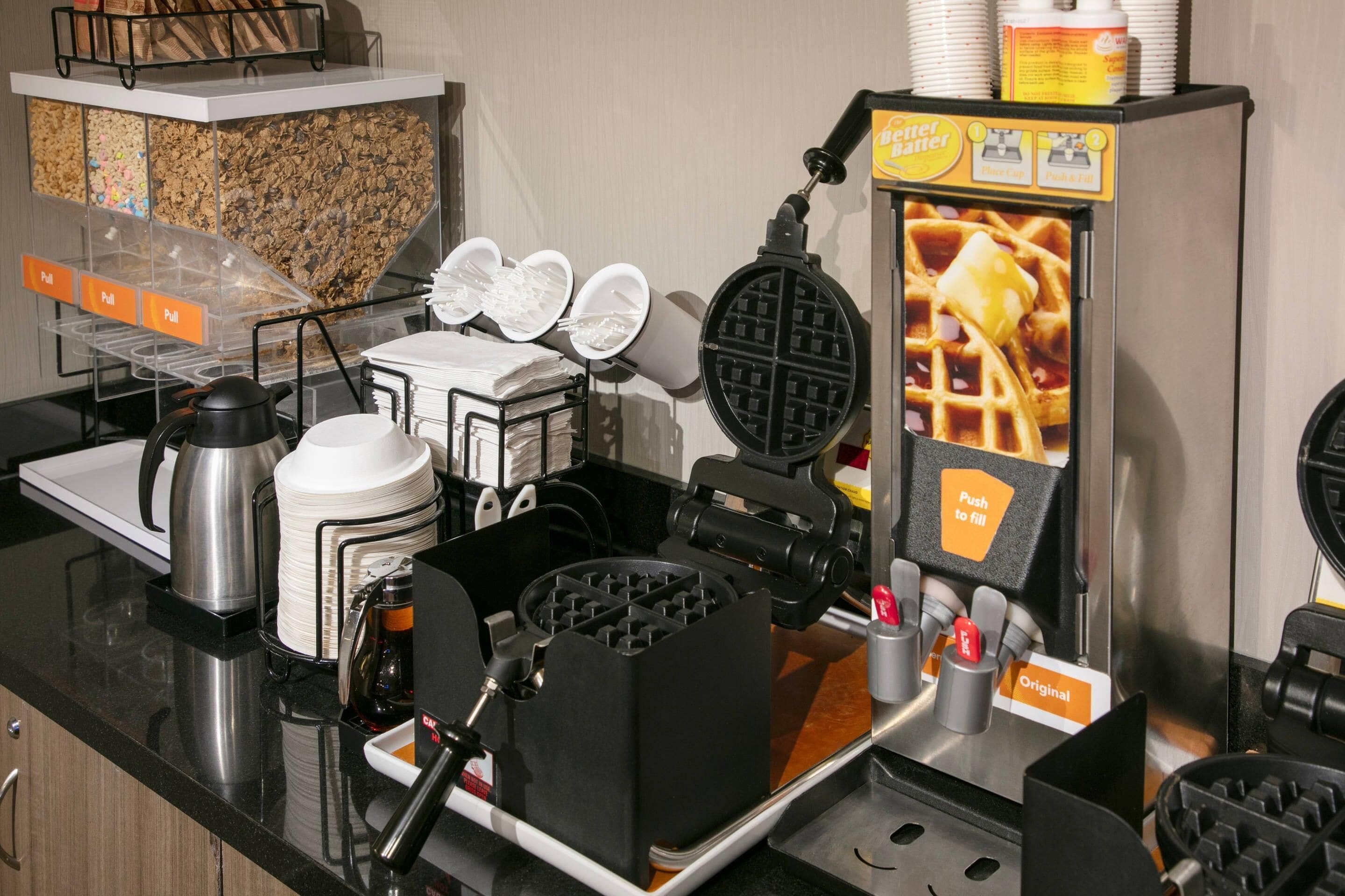 Un coin dédié aux gaufres, avec un appareil à gaufres, des assiettes et une machine à café.