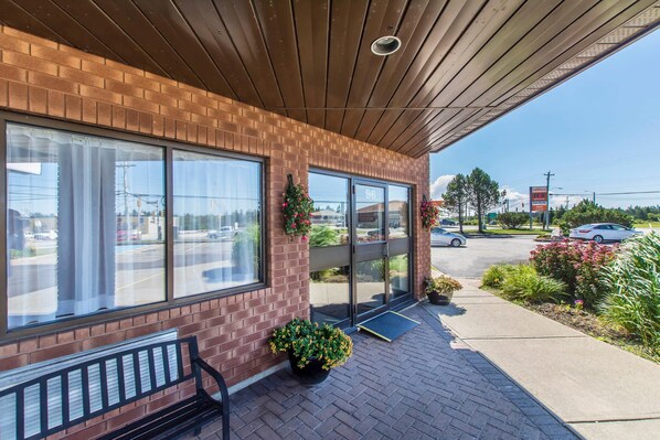 A brick building with large windows, a covered patio, and potted plants. - Comfort Inn (Yarmouth)