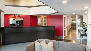 A reception area with a black counter, red walls, and a grey sofa with patterned cushions.