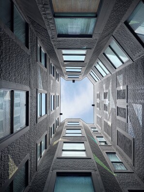 A modern building with a central atrium, multiple skylights, and a view of the sky. - Axiom Hotel (San Francisco)