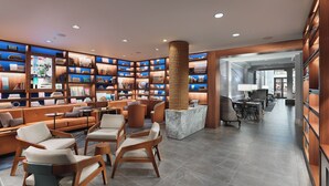 A modern library with bookshelves, comfortable seating, and a central pillar.