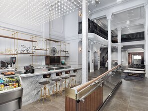 A modern bar area with a marble countertop, gold bar stools, and a glass enclosure with beverages. - Axiom Hotel (San Francisco)