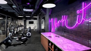 A gym with exercise equipment, a neon sign reading "Workout", and a marble countertop with dumbbells.