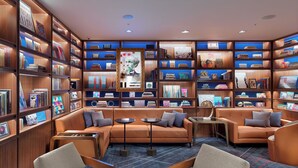 A modern library with leather sofas, bookshelves, and a central art piece.