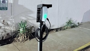 An electric vehicle charging station with a green light, a sign indicating it is for electric vehicles only while charging, and a cable connected to it. - Rodeway Inn Enid South (Enid)