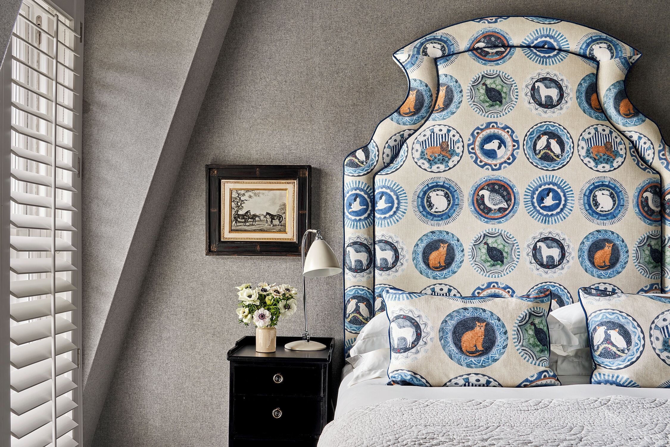 A bedroom with a bed, a nightstand, a lamp, and a framed picture on the wall.