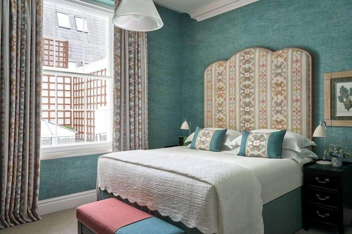 A bedroom with a bed, curtains, a window, and a nightstand.