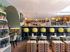 A bar area with seating, shelves with bottles, and potted plants. - Dorset Square Hotel, Firmdale Hotels (London)