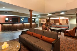 A lobby with a reception desk, seating area, and a fireplace.