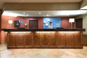A reception desk with a wooden finish, a blue wall with a Holiday Inn Express sign, and a tiled floor. - Holiday Inn Express Show Low by IHG (Show Low)