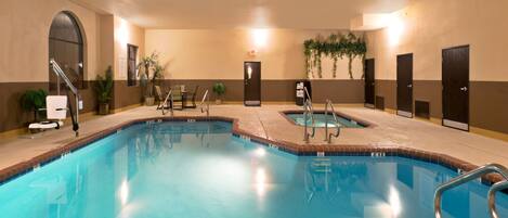 A hotel swimming pool with multiple lanes, lounge chairs, and a seating area.
