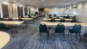 A conference room with multiple tables and chairs, carpeted floor, and a large screen at the front. - Holiday Inn Express Show Low by IHG (Show Low)