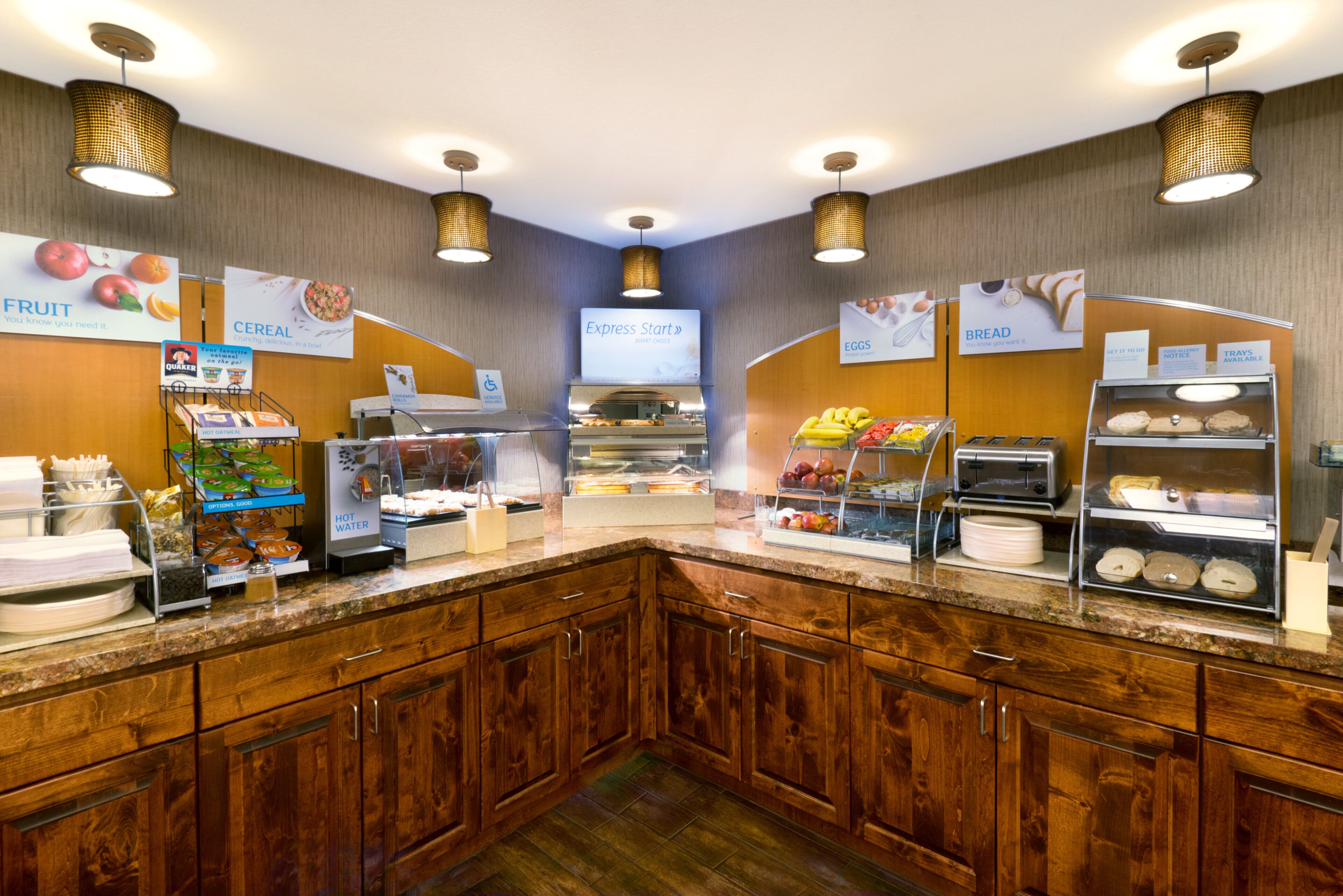 A self-service breakfast area with various food options, including cereal, eggs, and bread, and a hot water station.