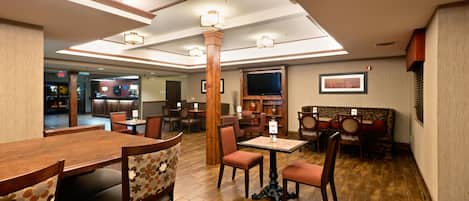 A restaurant with wooden tables and chairs, a television, and a fireplace.