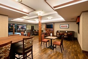 Un restaurante con mesas y sillas de madera, un televisor y una chimenea.