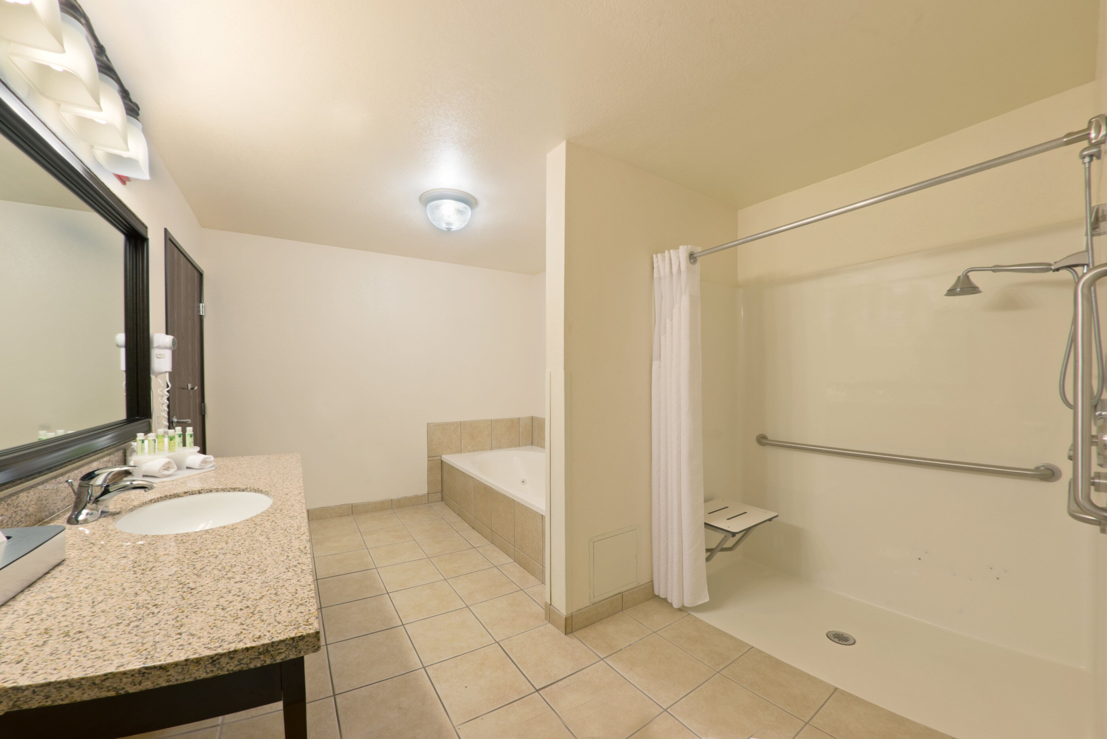 Une salle de bain équipée d’un lavabo, d’un miroir, d’une douche et de toilettes.