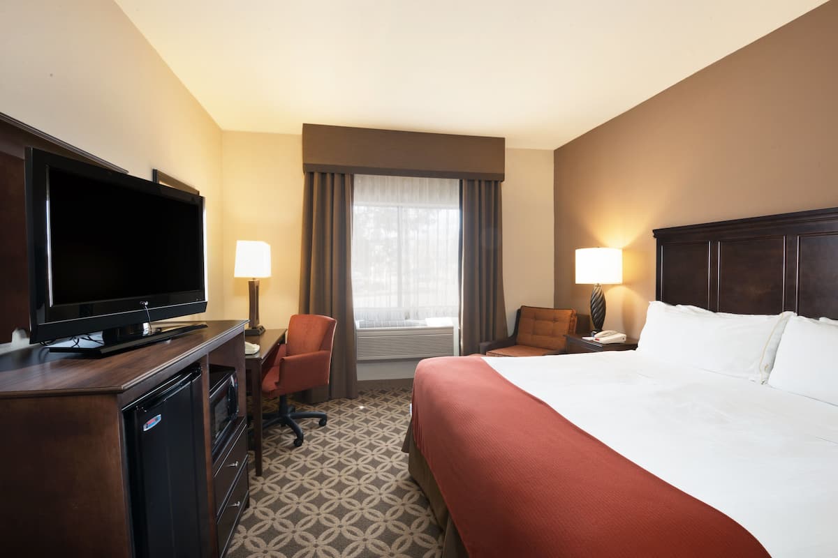 A hotel room with a bed, a TV, a desk, and a chair.