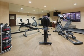 A gym with various exercise equipment including treadmills, an elliptical, and weight machines.