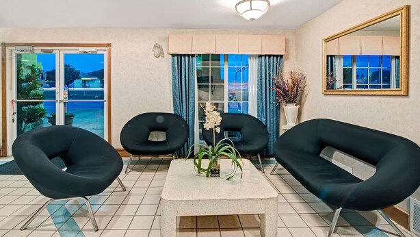 A room with two black chairs, a table with a vase of flowers, and a large window with curtains. - Day Star Dallas South (Dallas)