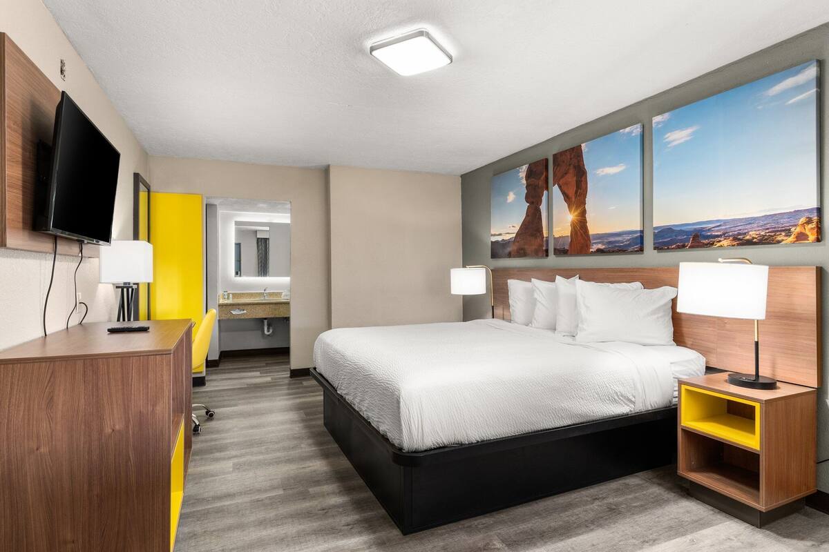 Ein Hotelzimmer mit Bett, Schreibtisch, Fernseher und Bildern an der Wand.