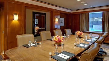 A conference room with a long wooden table, leather chairs, and floral centerpieces.