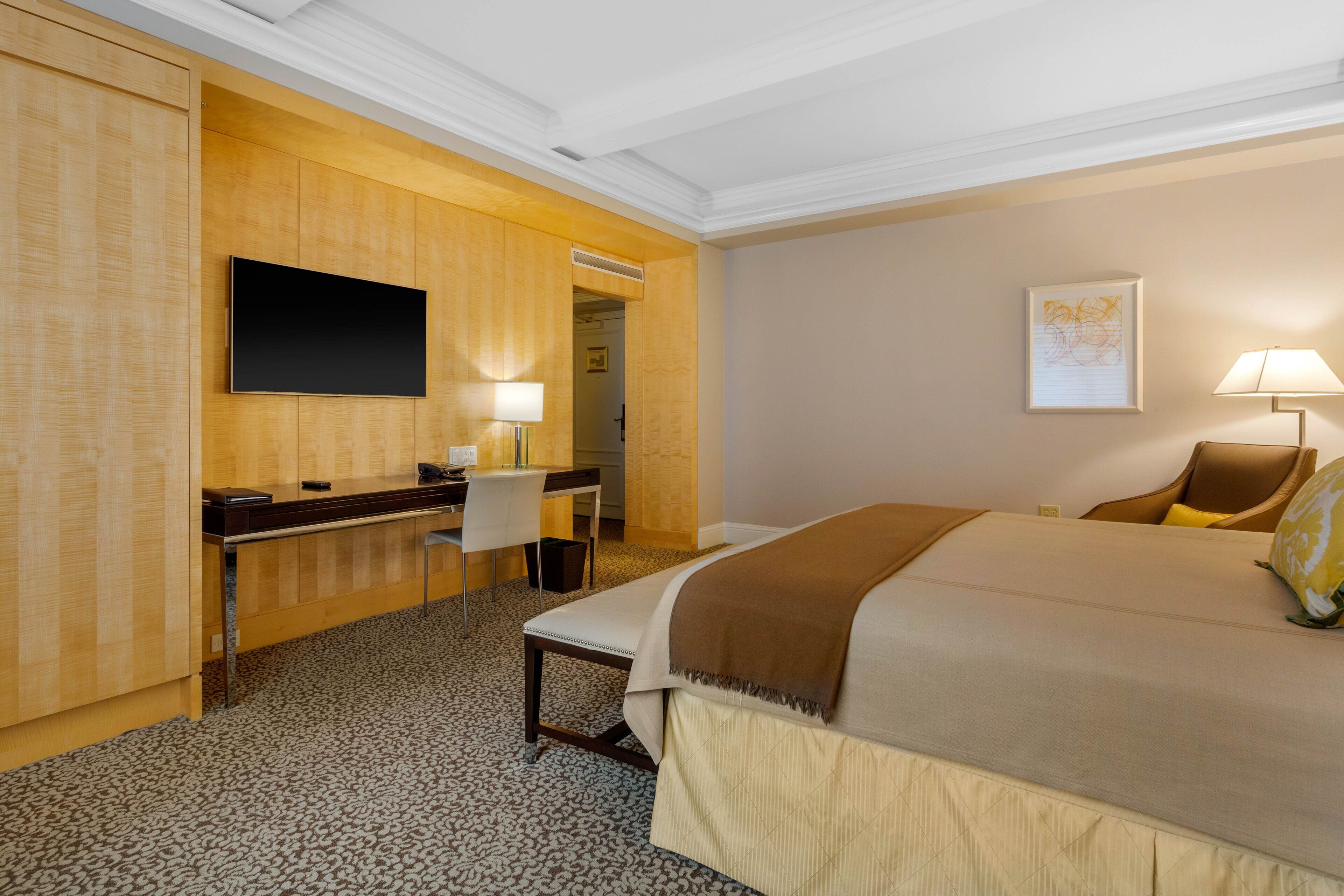 Ein Hotelzimmer mit Bett, Schreibtisch, Stuhl und Flachbildfernseher.