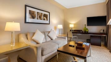 Habitación de hotel moderna con sofá, una mesa de centro, televisión y escritorio con lámpara.