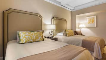 A hotel room with two beds, each with a headboard, a bedside table with a lamp, and a framed artwork on the wall.