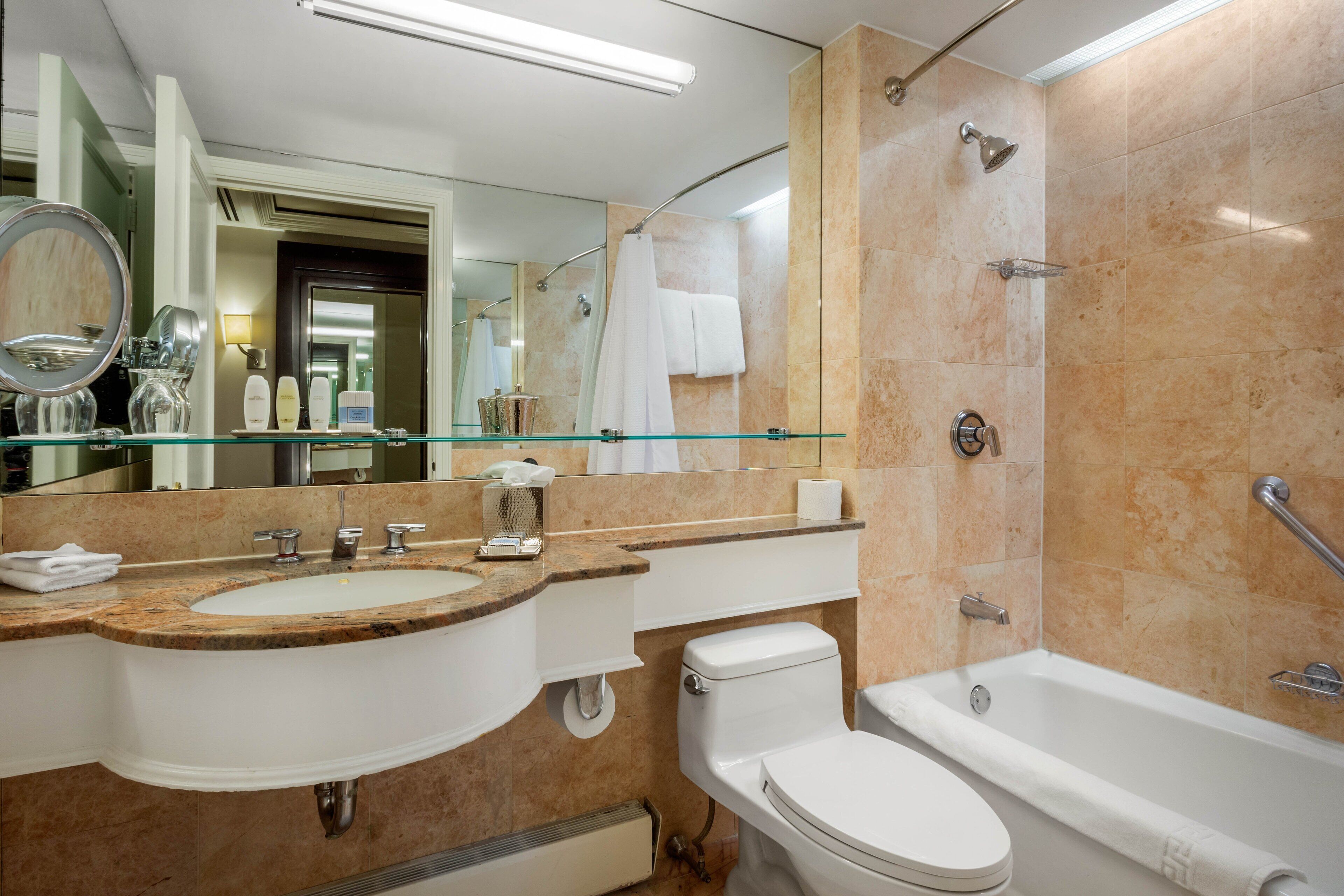 A modern bathroom with a glass-enclosed sink, a toilet, and a bathtub.