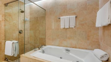 A modern bathroom with a glass-enclosed shower, a freestanding bathtub, and multiple white towels.