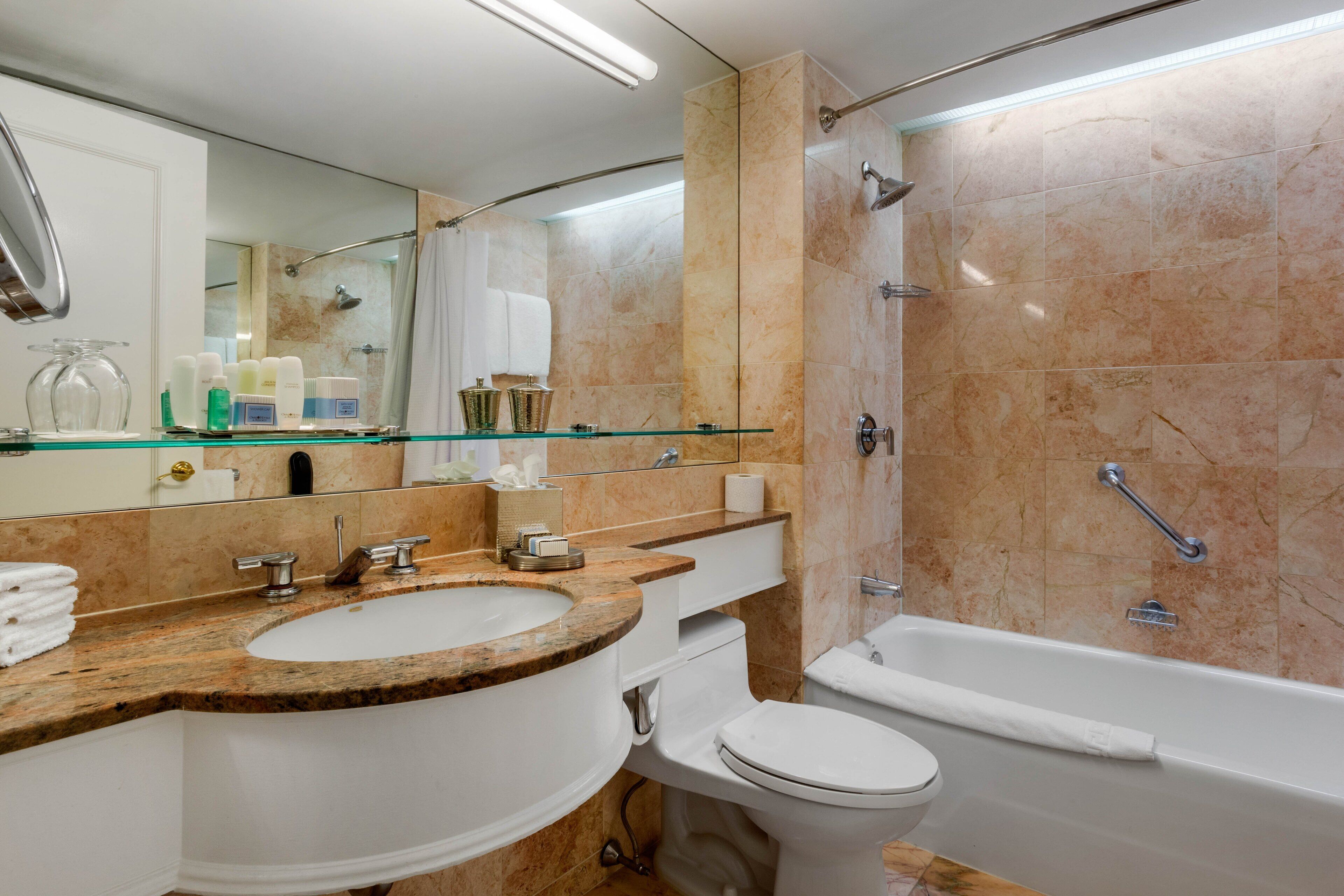 A modern bathroom with a marble sink, a glass shower enclosure, and a white toilet.