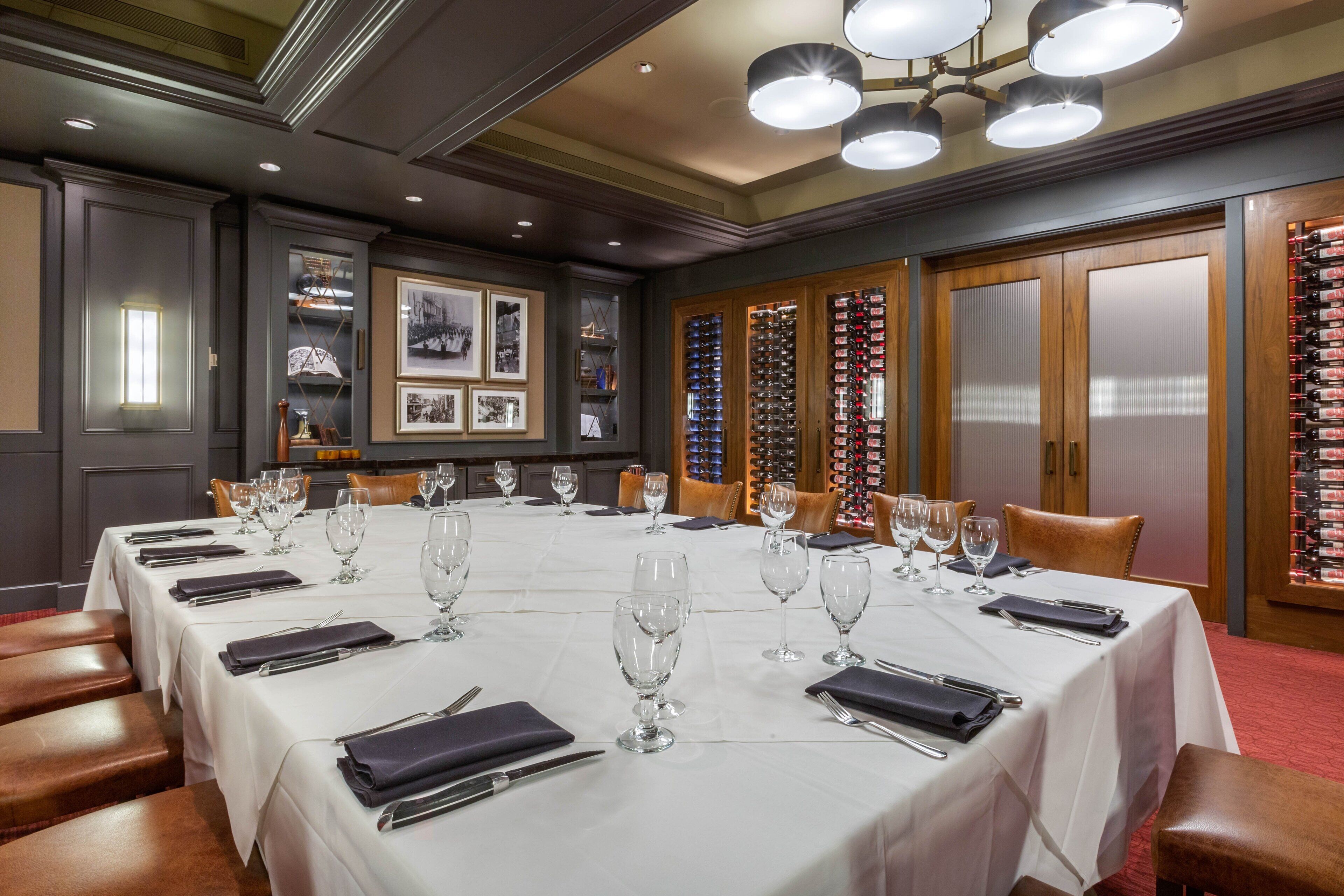A formal dining room with a long table set for a meal, surrounded by chairs.