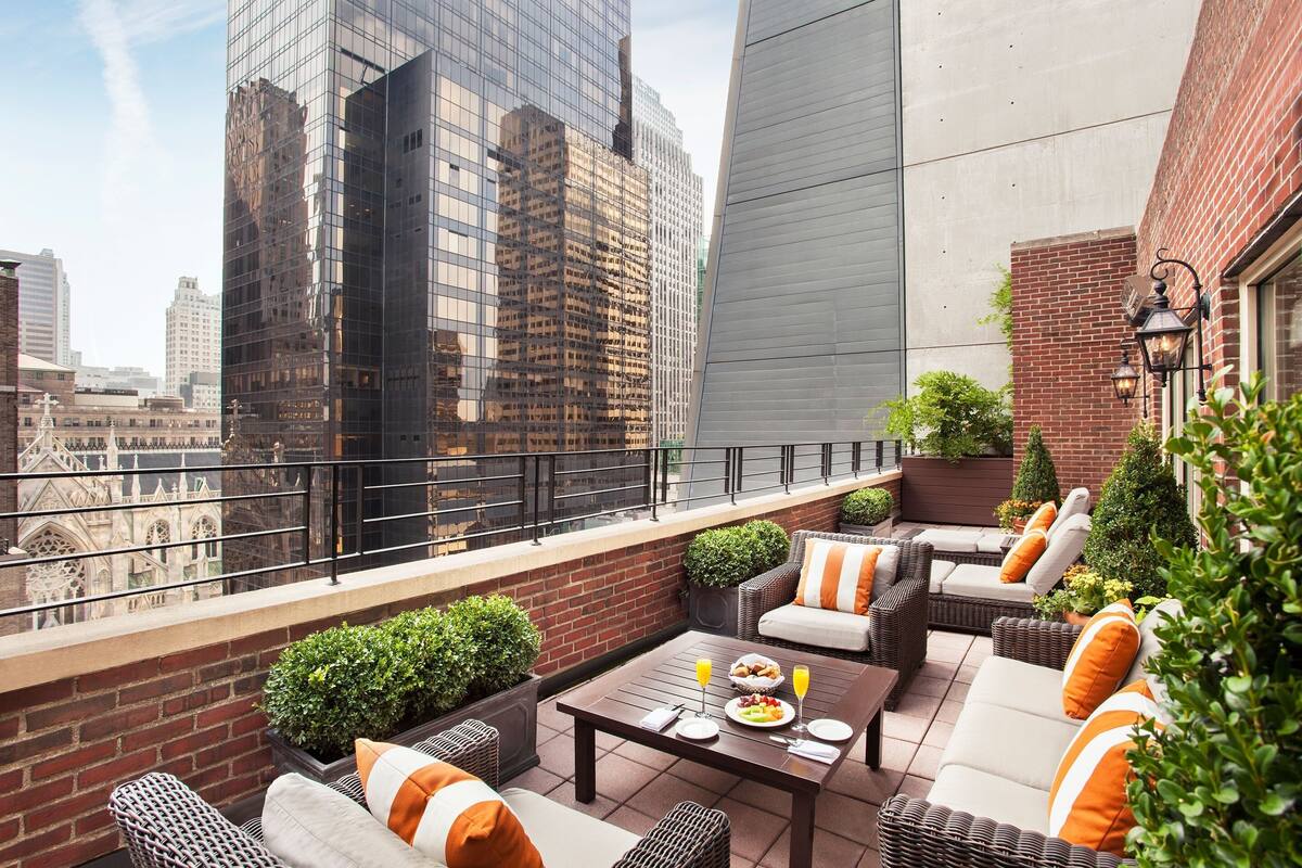 Terraço no telhado com área de estar ao ar livre, mesa de jantar e vista para edifícios da cidade.