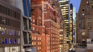 A high-rise building with a modern glass facade and a brick base, surrounded by other buildings with various architectural styles.