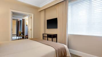 Una habitación de hotel con una cama grande, un escritorio, un televisor y una ventana con cortinas.