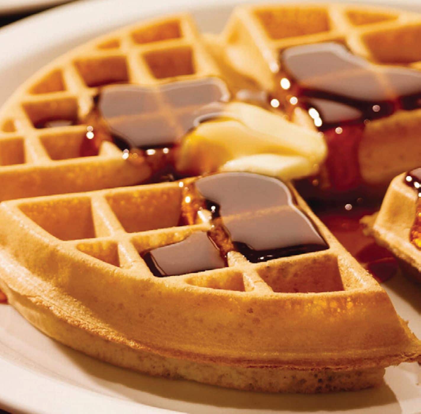 Primer pla d'un waffle amb xarop damunt d'un plat.