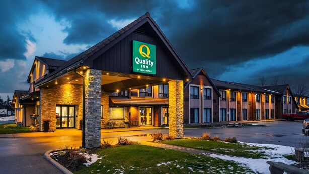 A Quality Inn hotel with a prominent green sign, stone facade, and multiple windows. - Quality Inn (Barrie)